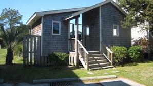 Ein eingeschossiges Haus mit einer Veranda und einer Treppe, die zum Eingang führt.