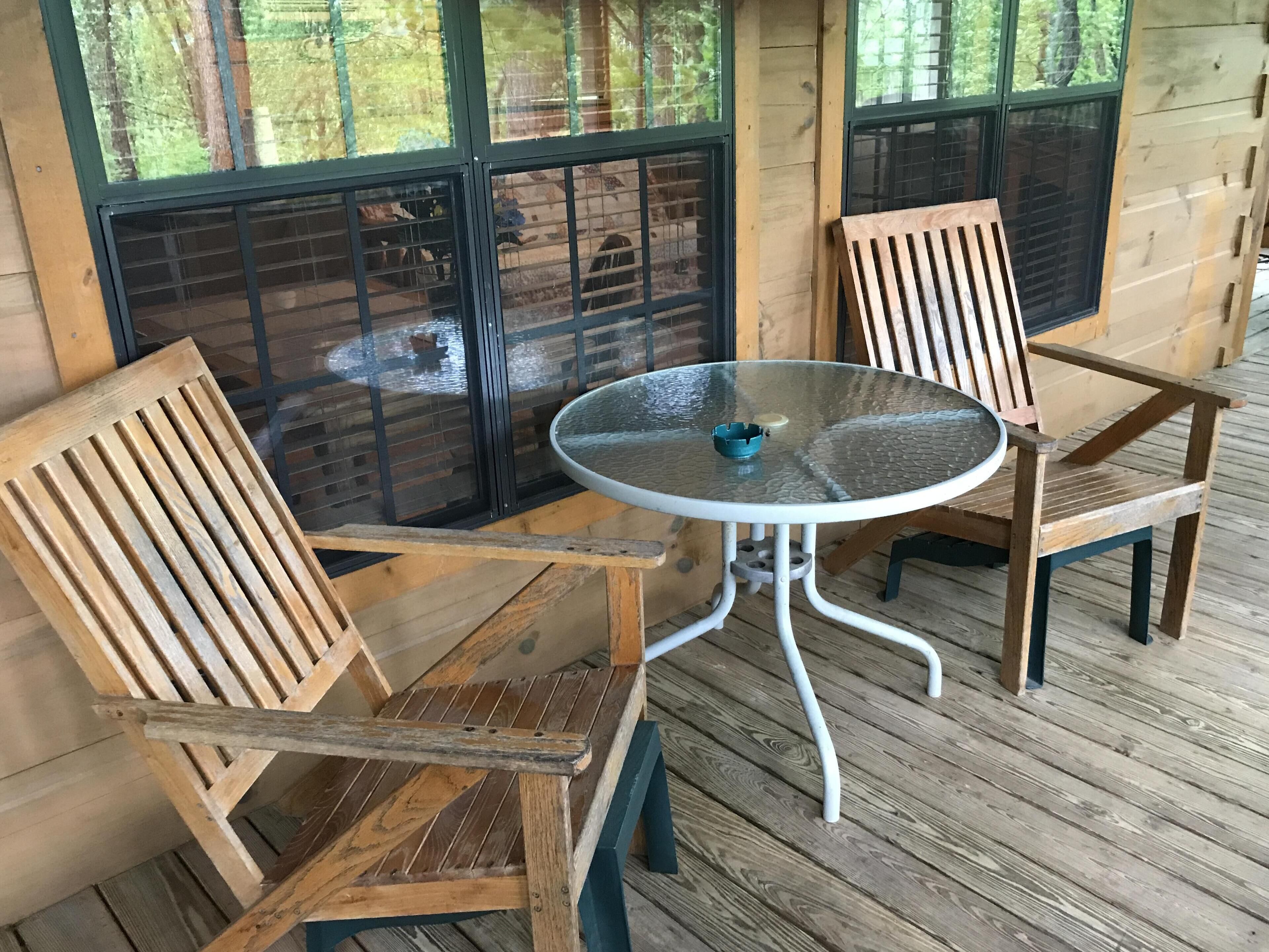 Eine Holzterrasse mit zwei Stühlen und einem runden Tisch.