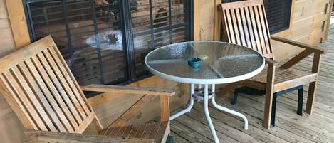 Eine Holzterrasse mit zwei Stühlen und einem runden Tisch.
