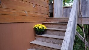 Eine Holztreppe mit einem Blumentopf mit gelber Blume auf der ersten Stufe.