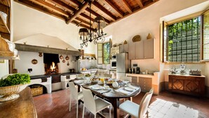 A rustic kitchen with a fireplace, wooden beams, and a dining area with a round table and chairs. - Exclusive 7BR-8BA Villa with pool, a few mins from town, yet in the countryside (Impruneta)