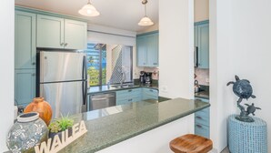 Una cocina moderna con armarios color turquesa, electrodomésticos de acero inoxidable y una isla central.