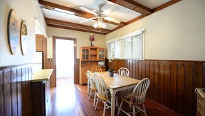Un coin repas avec une table et des chaises en bois, un ventilateur de plafond et un meuble en bois orné d’une plante.