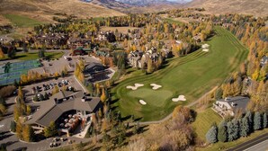 Un parcours de golf doté d’un club-house, d’un parking et de bâtiments résidentiels, situé dans une zone vallonnée.