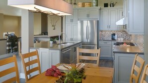 Une cuisine moderne dotée d’appareils électroménagers en acier inoxydable, d’un îlot central et de meubles de couleur gris clair.