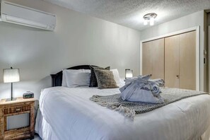 Ein Schlafzimmer mit Bett, Nachttisch, Lampe, Klimaanlage und Kleiderschrank.
