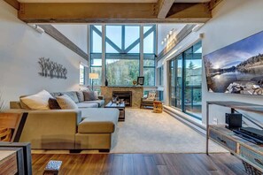 Ein modernes Wohnzimmer mit Kamin, großen Fenstern und Blick ins Freie.