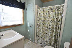 A bathroom with a sink, toilet, and shower curtain.