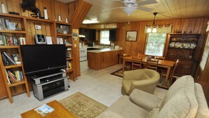 Una sala de estar acogedora con televisor, estanterías, sofá y comedor.
