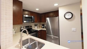 A modern kitchen with stainless steel appliances, wooden cabinets, and a built-in microwave. - Renovated Ground Floor Condo. Spacious Floor Plan, Pool & Hot Tub Onsite (Whistler)
