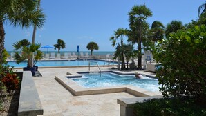 Ein Poolbereich mit mehreren Pools, Liegestühlen und Palmen.