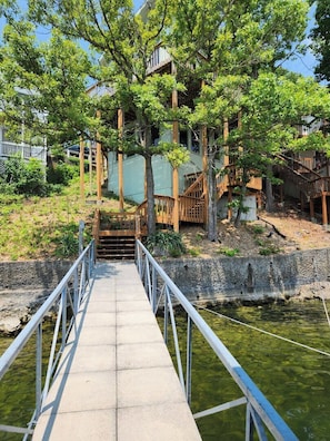 A bridge leading to a traditional Japanese-style building with wooden structures and a clear view of the surrounding greenery.
