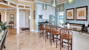 A spacious kitchen with a central island, white cabinetry, and modern appliances.