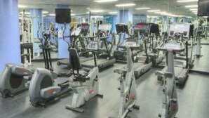 A gym with multiple exercise machines, including treadmills and elliptical trainers.