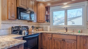 A kitchen with wooden cabinets, a stainless steel stove, and a window with a view of a house. - Ridge Condo 2672 - Upgraded With Great Views and Elkhorn Resort Amenities (Elkhorn)