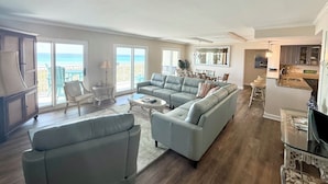 A spacious living area with a large sectional sofa, a dining table, and a kitchen area.