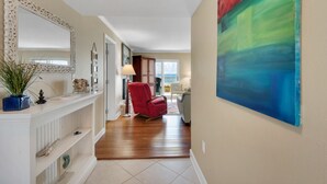 A hallway with a white console table, a red armchair, and a large abstract painting on the wall.