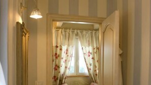Een badkamer met een wastafel, een spiegel, een kroonluchter en een raam met bloemen gordijnen.