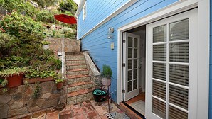 Ein blaues Haus mit einer Steinstufe, einer Fußmatte und einem Blumentopf.