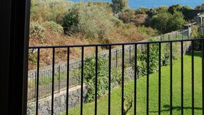 A balcony with a view of the sea and surrounding vegetation. - Three room apartment :Seafront residence with pool and garden (Santa Tecla di Acireale)