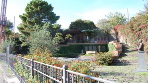 A garden with a statue, a stone bench, and a paved pathway. - Three room apartment :Seafront residence with pool and garden (Santa Tecla di Acireale)