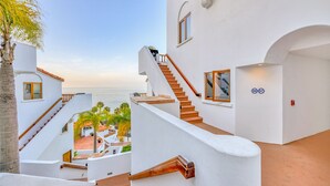 A modern white building with a staircase leading to a balcony overlooking a beach. - H157: Bright Villa, Sweeping Ocean Views, Golf Cart, WIFI (Avalon)