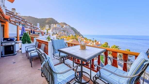 A terrace with outdoor seating, a grill, and a view of the ocean and hillside buildings. - H157: Bright Villa, Sweeping Ocean Views, Golf Cart, WIFI (Avalon)