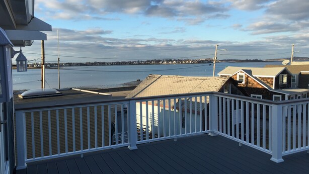 A deck with a railing overlooking a body of water and a distant shoreline.