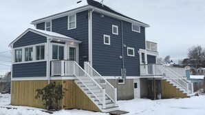 A two-story residential building with a covered porch and a staircase leading to the upper floor.