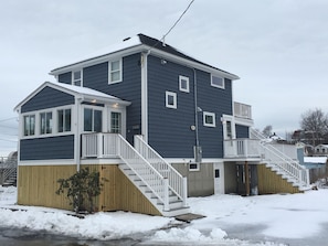 A two-story residential building with a covered porch and a staircase leading to the upper floor. - Newly renovated Beach House - near Boston (Weymouth)