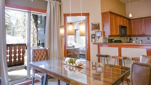 A dining area with a glass table, cushioned chairs, and a view of a balcony. - Wanderlust Suite (with AC unit!) by Cottonwood Lodging (Solitude)