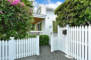 Une maison blanche avec un porche et une clôture en bois peinte en blanc.