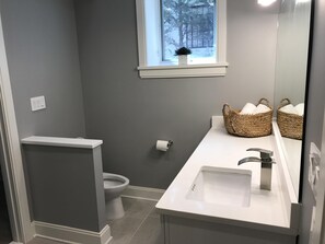 A bathroom with a toilet, a sink, and a window above the sink. - Luxury Condo 2br close to Metro & NIH Walter Rees/Sightseeing/Museums/Zoo/shops (Chevy Chase)