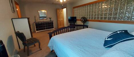 Une chambre à coucher comprenant un lit, une commode, une chaise et un téléviseur.