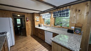 Una cocina con armarios de madera, encimeras de granito, una estufa y un lavabo.