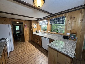 Une cuisine avec des armoires en bois, des comptoirs en granit, une cuisinière et un évier.