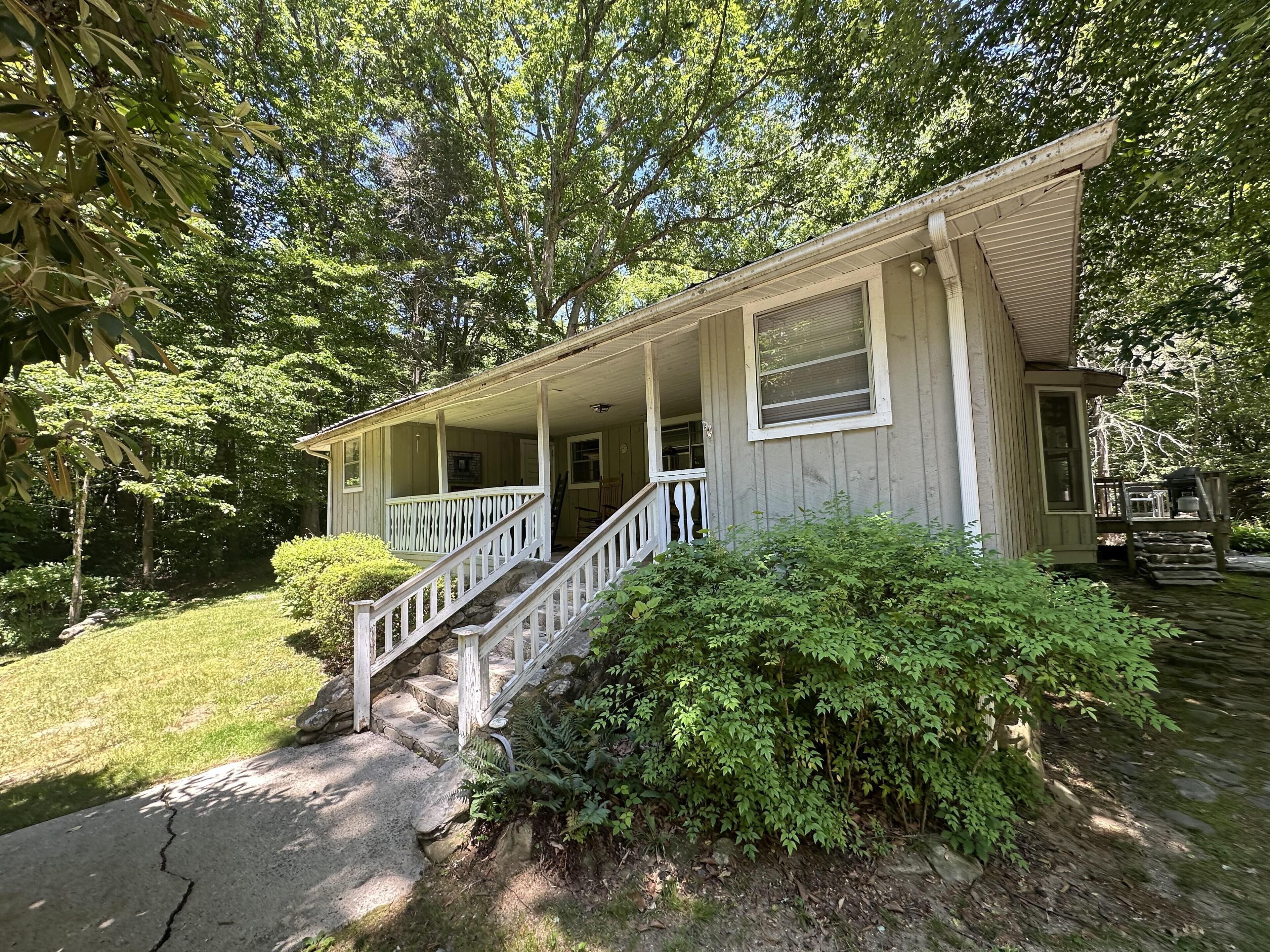 A two-story house with a porch, stone steps, and a small deck.