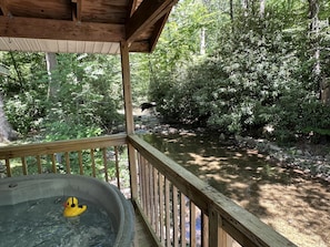 A wooden deck overlooking a natural area with a hot tub and a duck float.