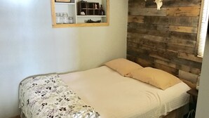 Un dormitorio con cabecera de madera, cama con ropa de cama floral, estante con adornos y un cráneo de ciervo montado en la pared.