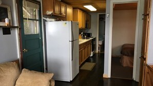 Una cocina compacta con armarios de madera, un refrigerador blanco y una pequeña encimera.