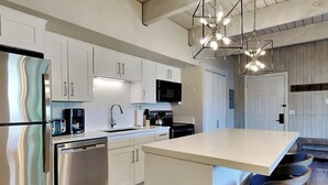 A modern kitchen with white cabinetry, stainless steel appliances, a central island with bar stools, and pendant lighting. - 🌲Timberline C2D Deluxe 2-Bedroom ~Hot Tub~Pool~WiFi~Ski-in/out~Local Shuttle🌲 (Snowmass Village)