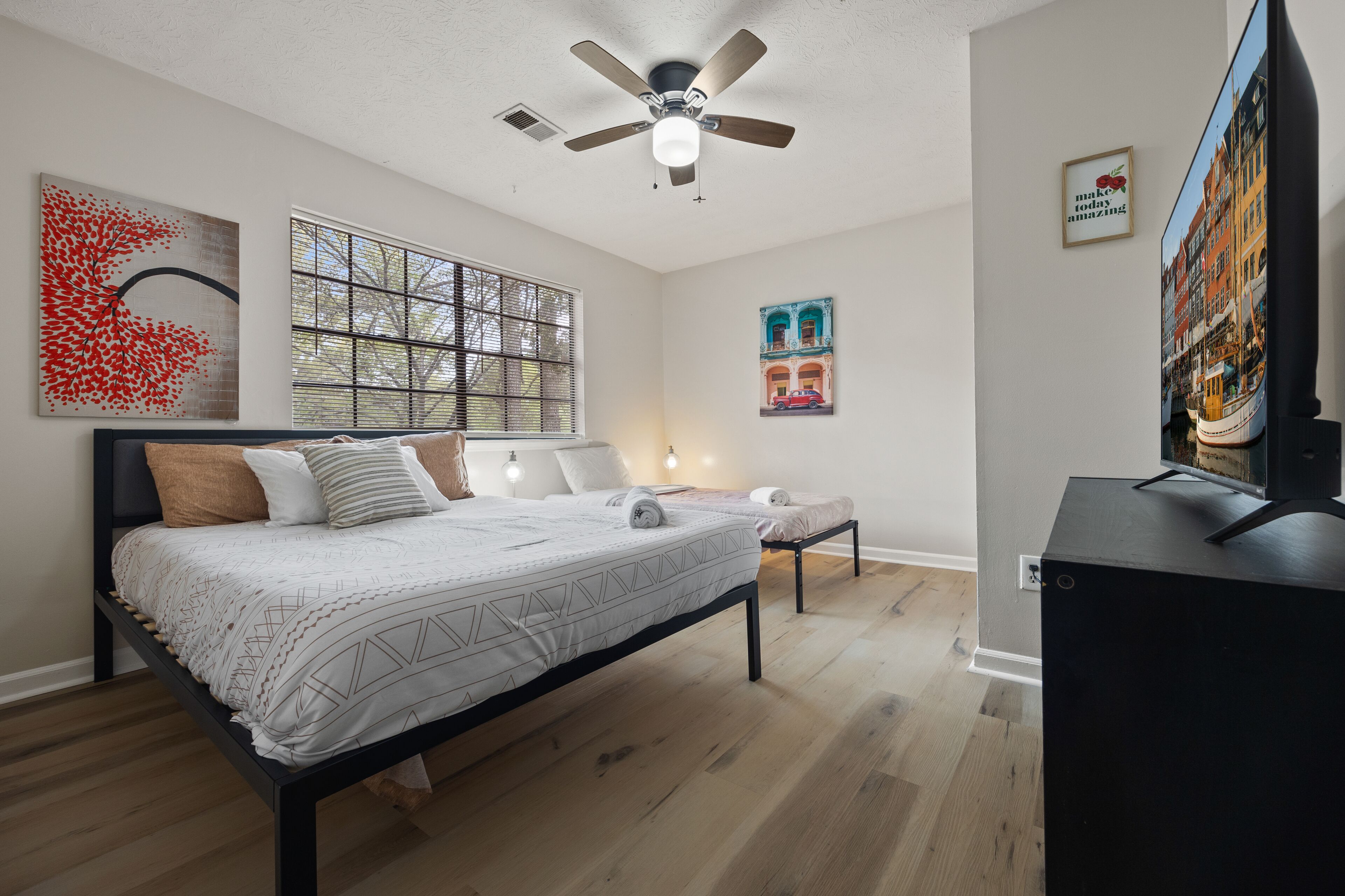A modern bedroom with a bed, a desk, and a ceiling fan.