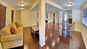 Un vaste espace de vie doté d’un plancher en bois, d’un canapé et d’une table à manger avec des chaises.