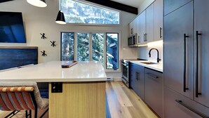 A modern kitchen with a large island, built-in appliances, and a view of a snowy landscape through large windows. - 🌲Timberline A3A Premier 2-Bedroom + Loft ~ 3/bath ~Hot Tub~Pool~WiFi~Ski-in/out🌲 (Snowmass Village)