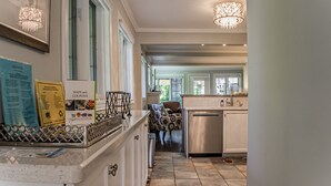 A kitchen with a countertop, a refrigerator, and a dining area with a chair. - La Vignette, Dog Friendly Bungalow Close to the Lakefront (Niagara-on-the-Lake)