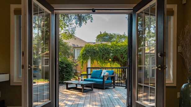 A sliding glass door leading to an outdoor patio with a blue sofa and a coffee table. - La Vignette, Dog Friendly Bungalow Close to the Lakefront (Niagara-on-the-Lake)