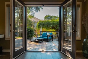 Uma porta de vidro deslizante dá para um pátio externo com um sofá azul e uma mesa de centro.