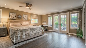 A spacious bedroom with a large bed, a desk, and a view through the glass doors. - La Vignette, Dog Friendly Bungalow Close to the Lakefront (Niagara-on-the-Lake)