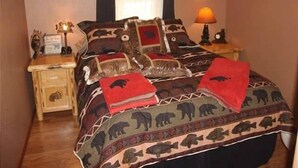 Ein Schlafzimmer mit einem gestreiften Bett, einem Nachttisch mit Lampe und einem gerahmten Bild an der Wand.