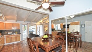 A spacious kitchen with wooden cabinets, a dining table with chairs, and a ceiling fan. - 211CLU: Home with Deck, Golf Cart, 1 Block to the Beach, Pet Friendly, WIFI - 21 (Avalon)